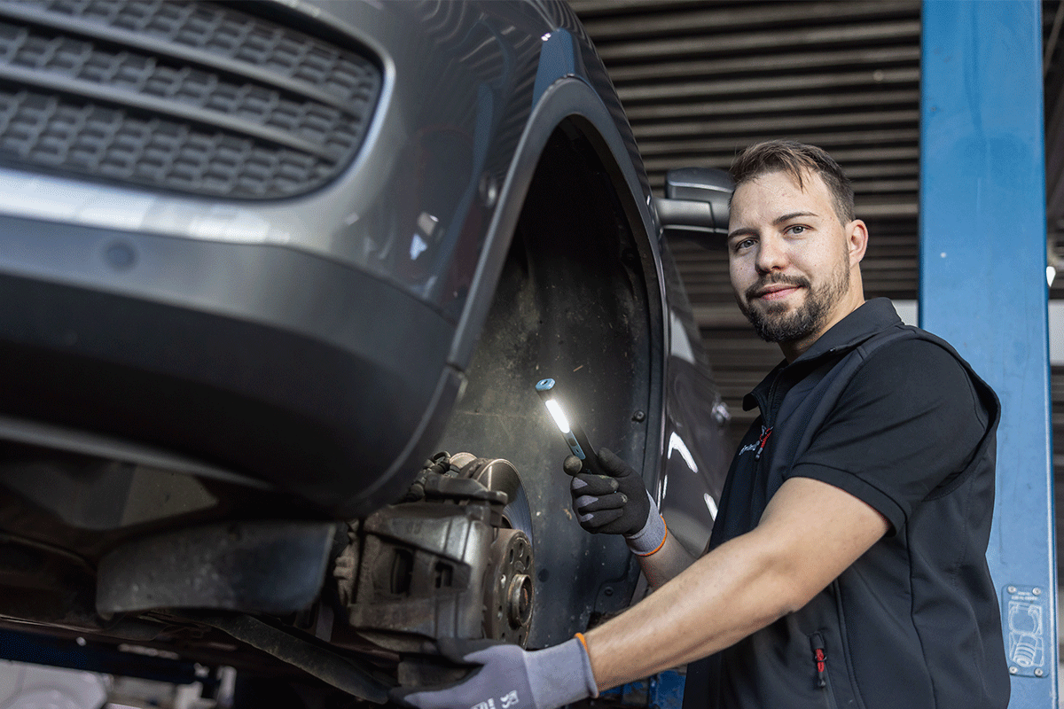 Werkstattmitarbeiter prüft Bremsenzustand