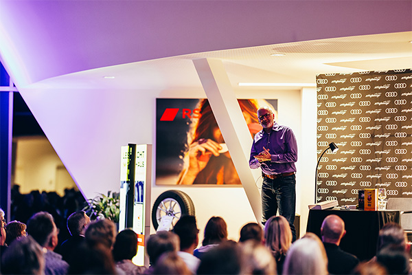 Autor Peter Grandl steht vor einem Publikum.