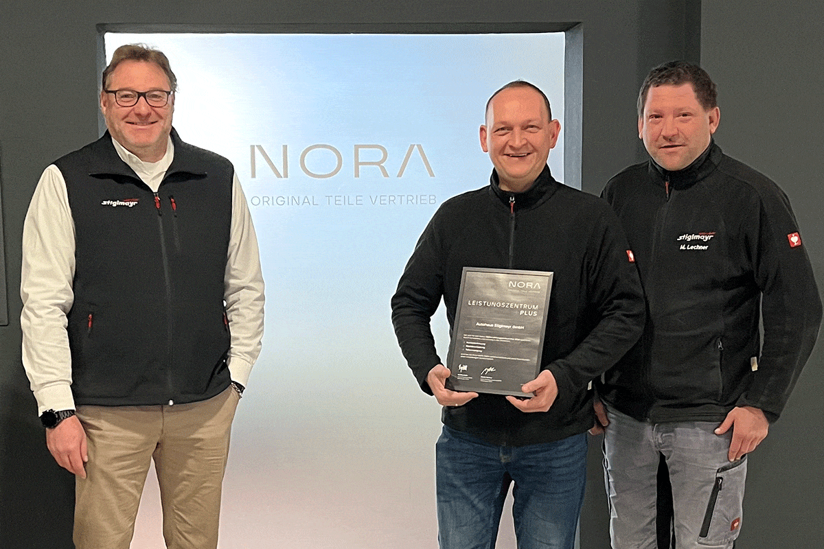 Teiledienstleiter Andreas Rossol, NORA-Experte Klaus Priller und NORA-Kundenbetreuer Martin Lechner stehen mit der Auszeichnung von einem NORA Aufsteller.